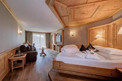 a bedroom with a large bed with a wooden ceiling at Quellenhof Luxury Resort Passeier in San Martino