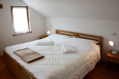 a bedroom with a bed with white sheets and a window at Casa Teresa Martin in San Vigilio Di Marebbe
