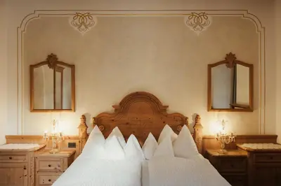 a bedroom with a large wooden bed with two mirrors at Hotel Colbricon Beauty & Relax in San Martino di Castrozza