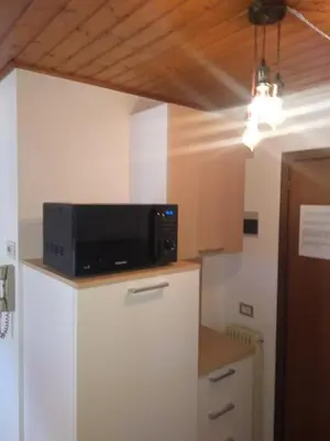 a kitchen with a microwave on top of a refrigerator at Steila da Mont Campitello in Campitello di Fassa