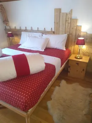 a bedroom with two beds and a table with a lamp at Steila da Mont Campitello in Campitello di Fassa
