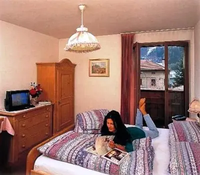 a woman laying on a bed in a bedroom at Sport Hotel Sass Maor in Predazzo