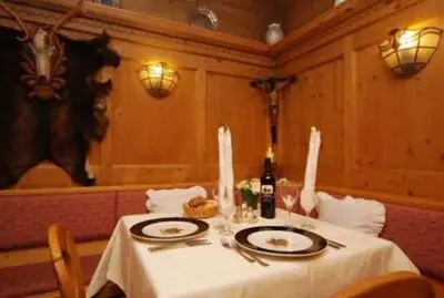 a table with a white table cloth and a bottle of wine at Sport Hotel Sass Maor in Predazzo