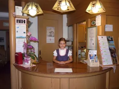 a little girl sitting at a counter in a restaurant at Sport Hotel Sass Maor in Predazzo