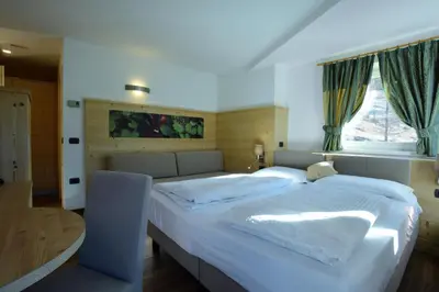 a bedroom with a large white bed with a window at Agritur Darial in Tesero