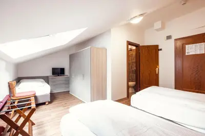 a bedroom with two beds and a desk at Hotel Panorama in Cavalese