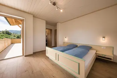 a bedroom with a large bed and a balcony at Steinkellerhof in Vollan