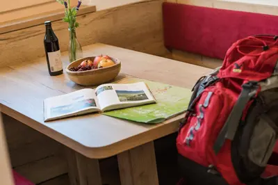 a table with a book and a bowl of fruit and a backpack at Steinkellerhof in Vollan