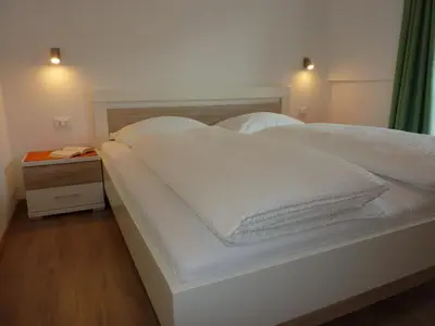 a white bed with two pillows and a night stand at Appartement Windisch in Tirolo