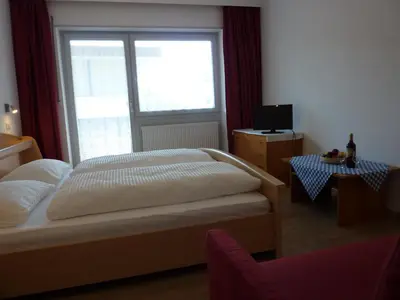a bedroom with a bed and a large window at Appartement Windisch in Tirolo