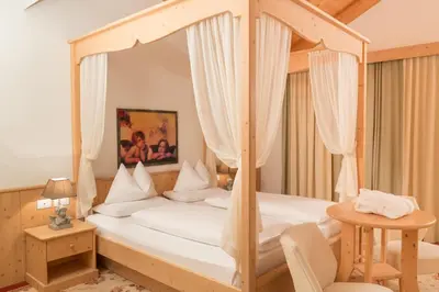 a bedroom with a canopy bed and a table at Boutique Hotel Olympia in San Vigilio Di Marebbe
