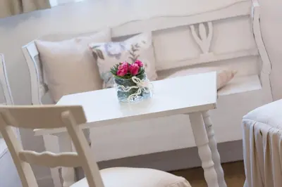 a white table with a vase of flowers on it at Boutique Hotel Olympia in San Vigilio Di Marebbe