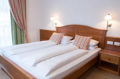 a large bed with white sheets and pillows at Boutique Hotel Olympia in San Vigilio Di Marebbe