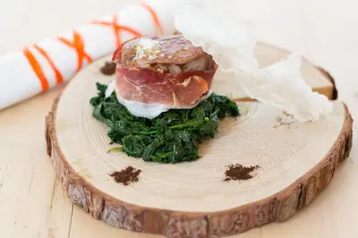 a sandwich on a wooden cutting board with greens at Boutique Hotel Olympia in San Vigilio Di Marebbe