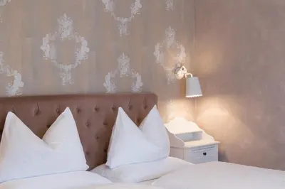 a bedroom with a bed with white pillows and a lamp at Boutique Hotel Olympia in San Vigilio Di Marebbe