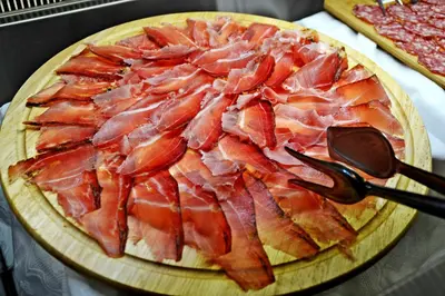a pizza with bacon on top of a wooden board at Agritur Scoiattolo in Coredo