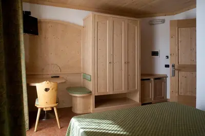 a bedroom with a bed and a cabinet and a chair at Agritur Scoiattolo in Coredo