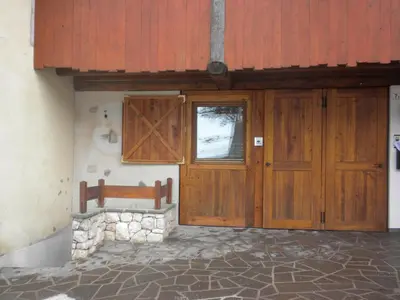 a wooden door and a bench in front of a building at Casa Litegosa in Panchia