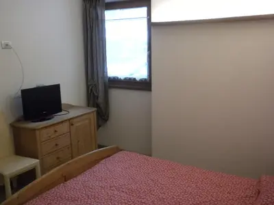 a bedroom with a bed and a tv and a window at Casa Litegosa in Panchia