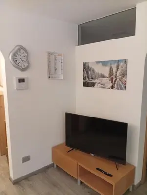 a flat screen tv sitting on a wooden stand in a living room at Casa Litegosa in Panchia