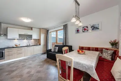 a kitchen and a living room with a table and a couch at Apartments Schönblick in Mühlbach