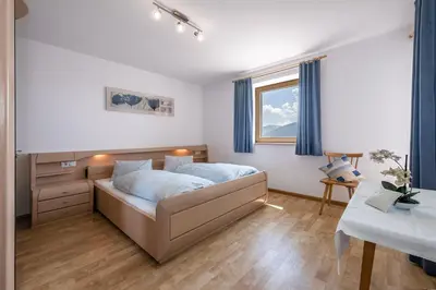 a bedroom with a bed and a desk and a window at Apartments Schönblick in Mühlbach