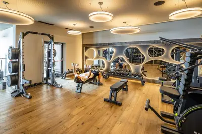 a gym with tread machines and a man laying on a bench in the middle at My Arbor - Dolomites in Bressanone