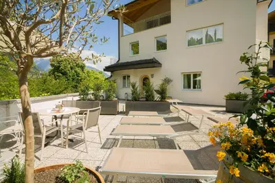 a patio with a table and chairs and a building at Villa am Gries in Lana