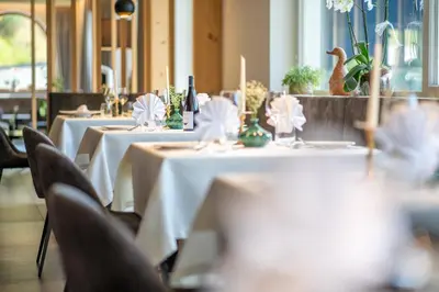 a row of tables with white table cloths and candles at Hotel Seehof in Monguelfo