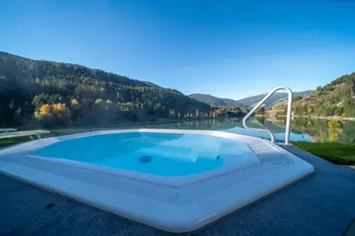 a table and chairs with a view of a lake at Hotel Seehof in Monguelfo