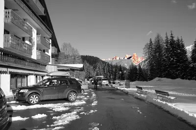 a car parked on the side of a snow covered street at Hotel Sole Family Hotel in Predazzo