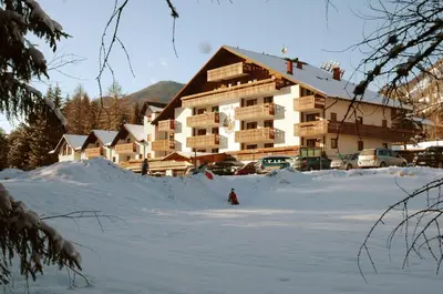 a large building with a lot of snow in front of it at Hotel Sole Family Hotel in Predazzo