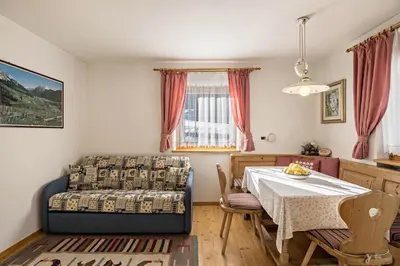 a bedroom with a table and a bed and a dining room at Apartments Primula in San Vigilio Di Marebbe