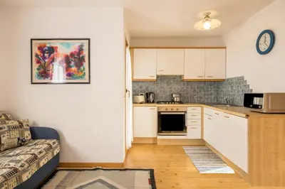 a kitchen with white cabinets and a couch in a room at Apartments Primula in San Vigilio Di Marebbe