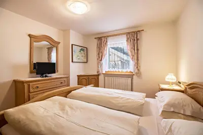 a bedroom with two beds and a tv and a mirror at Apartments Primula in San Vigilio Di Marebbe