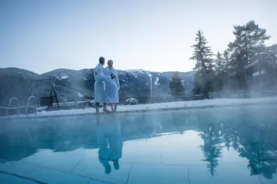 two people standing next to a swimming pool at Hotel Waldhof in Perca
