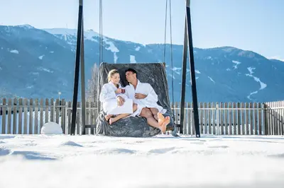 a man and a woman sitting on a swing at Hotel Waldhof in Perca