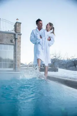 a man and woman standing next to a pool of water at Hotel Waldhof in Perca