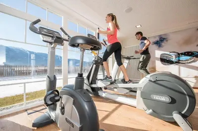 a man and a woman on a treadmill in a gym at Hotel Waldhof in Perca