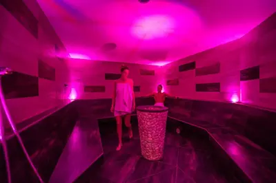 a woman standing in a room with pink lights at Hotel Waldhof in Perca