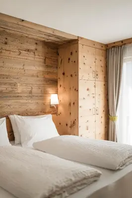 a bedroom with a bed with a wooden wall at Hotel Pider in La Valle