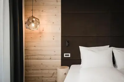 a bedroom with a white bed and a wooden wall at Hotel Pider in La Valle