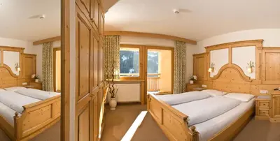 two beds in a room with wooden cabinets at Hotel Pider in La Valle