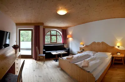 a bedroom with a large bed and a living room at Hotel Piné in Tires