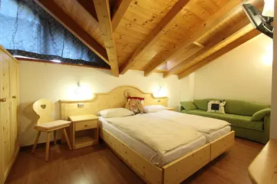 a bedroom with a large bed and a green couch at B.& B. Corradini in Castello di Fiemme