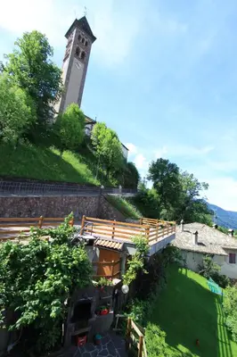 a building with a clock tower on top of a hill at B.& B. Corradini in Castello di Fiemme