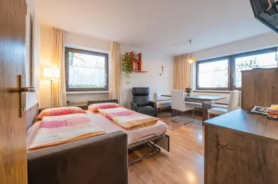 a bedroom with two beds and a dining room with a table at App Brunner in Valdaora