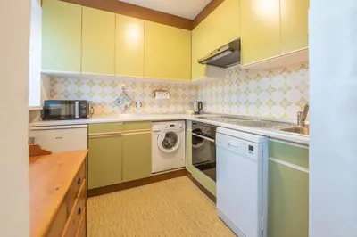 a kitchen with yellow cabinets and a washer and dryer at App Brunner in Valdaora