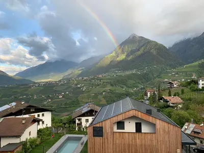 a rainbow in the sky over a town with mountains at Moar am Ort in Schenna