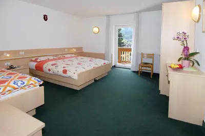 a hotel room with two beds and a balcony at Hotel Zanon in Ziano di Fiemme